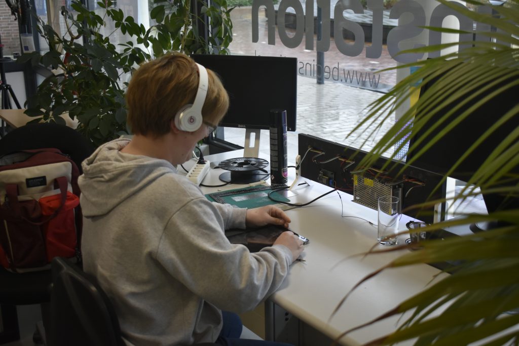 Jongedame die in een kantoor werkt met een koptelefoon en tablet omringt door beeldschermen en technologie