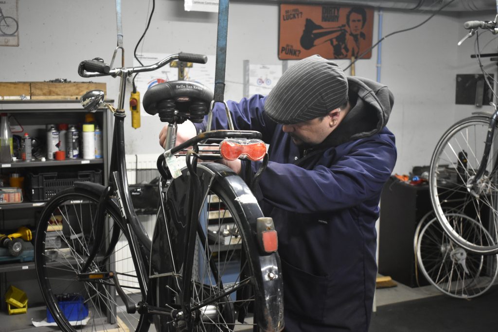 Fietsen maker die het fietszadel versteld van een zwarte oma fiets.